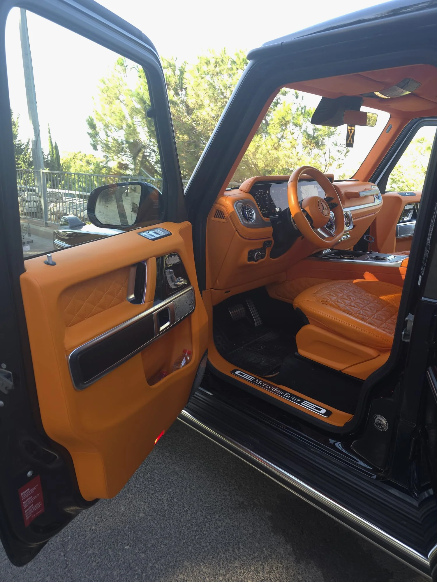 The G63's driver's door open, showing the dashboard, the steering wheel and a quilted orange leather driver's seat