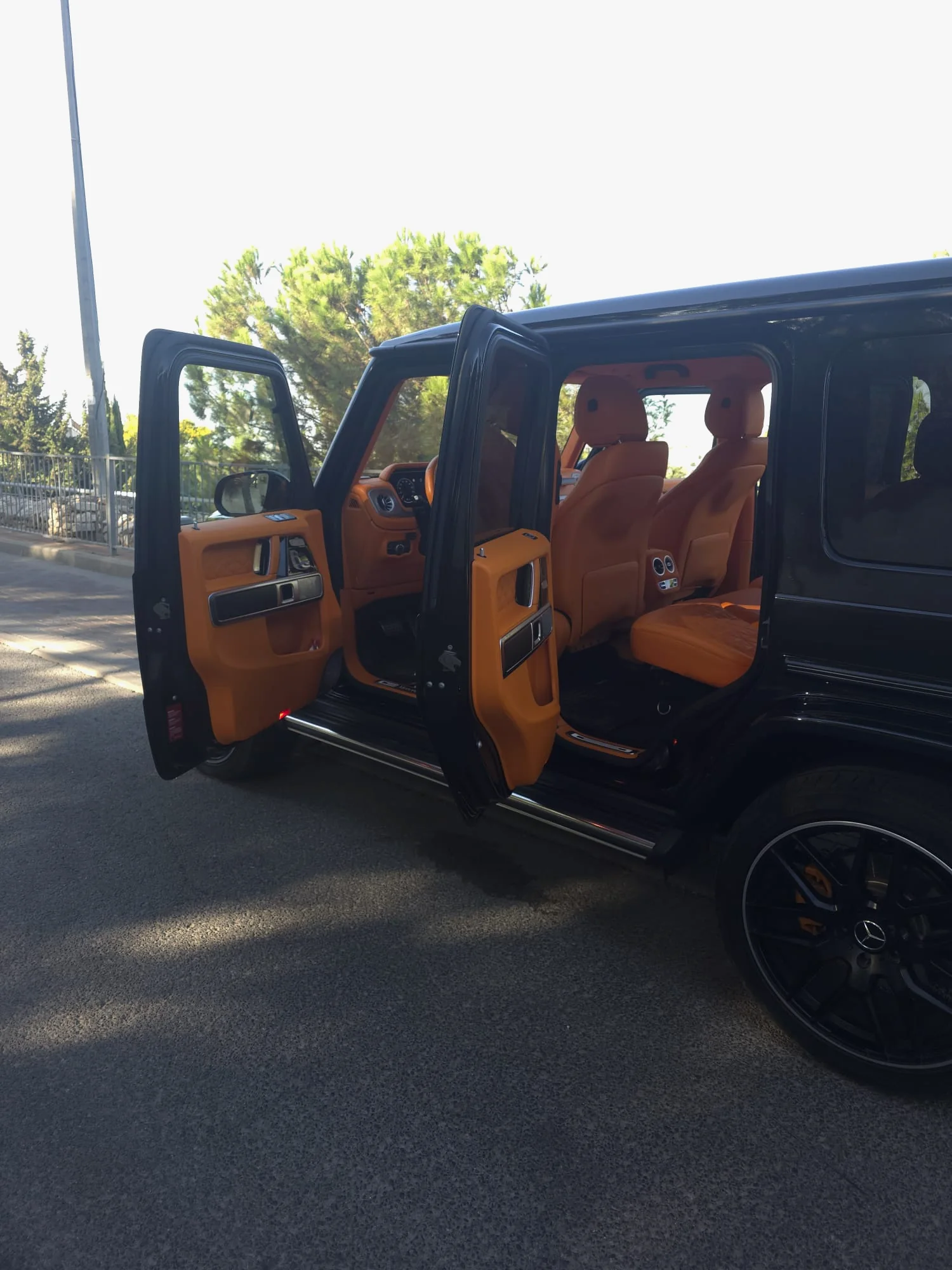 מרצדס G63 שחורה מהצד עם הדלתות הקדמית והאחורית פתוחות, מדרגת צד מבריקה וחישוק AMG שחור